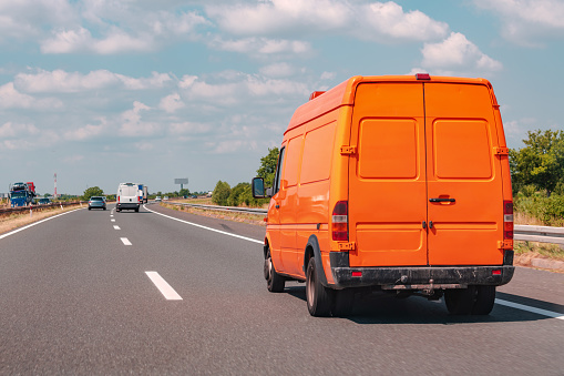Orange minivan on the road, transportation industry and delivery service