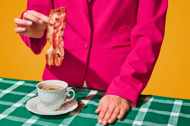 Woman putting fried bacon into cup with coffee over yellow background. Funny morning. Vintage, retro style interior. Food pop art photography. Woman putting fried bacon into cup with coffee over yellow background. Funny morning. Vintage, retro style interior. Food pop art photography. Complementary colors. Copy space for ad, text pop art photos stock pictures, royalty-free photos & images
