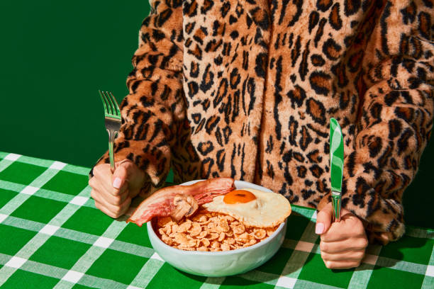 Plate of sweet cornflakes with milk, fried eggs and bacon on green tablecloth. Unordinary combination