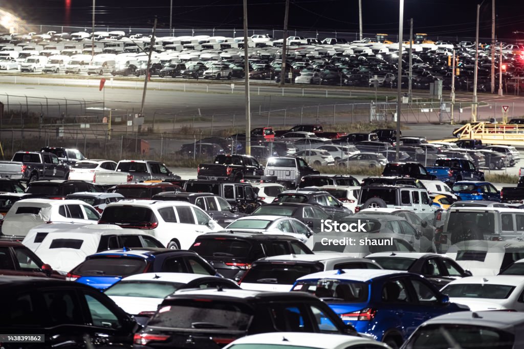 Vehicles at Autoport Vehicles shipped by rail await transport via roll-on/roll-off cargo ship. Brand logos removed. Car Dealership Stock Photo