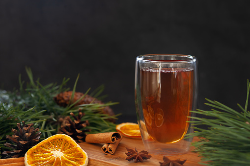 A cup of fresh fragrant tea with star anise spices, cinnamon sticks and dried oranges