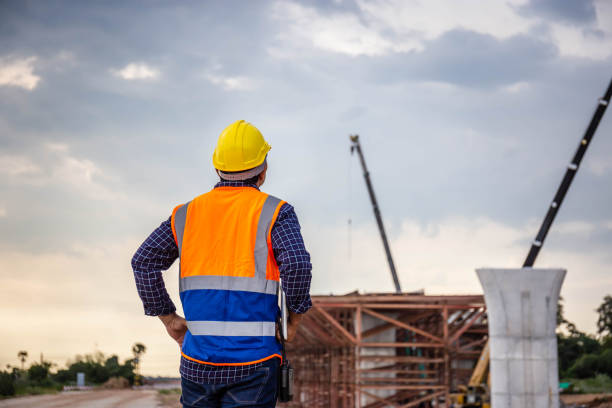 istock Rear view of Engineer under inspection and checking project at the building site, Foreman worker in hardhat at the infrastructure construction site 1438392295