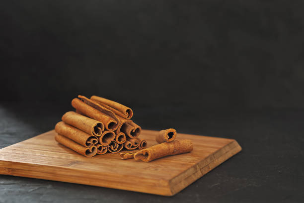 Fragrant cinnamon sticks on a wooden board on a black background