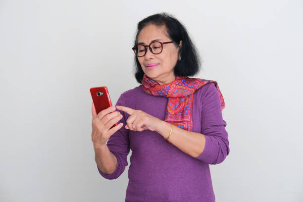 istock Asian elderly women smiling while using mobile phone 1438393946