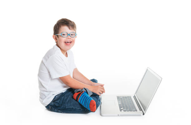 A young boy dressed as a businessman gives the thumbs up sign as there is some good business happening. He sits at his desk with retro computer and phone.