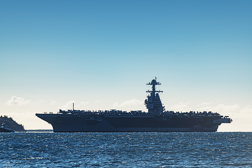 Navy aircraft carrier enters a harbour after offshore training exercises.