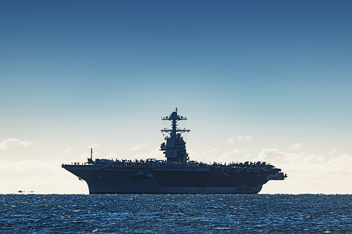 Navy aircraft carrier enters a harbour after offshore training exercises.