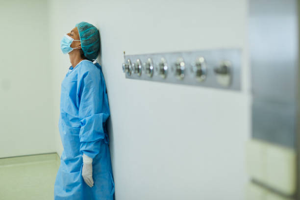 Using the wall for support this tired and distraught nurse recovers after poor result in the operating room stock photo