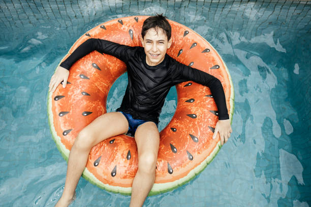 Teenage boy in a swimming pool on a float