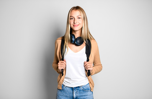 A Portrait of young beautiful student girl smiling looking at camera over white background.