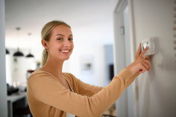 istock Woman Adjusting Central Heating Temperature At Home On Thermostat 1438399109
