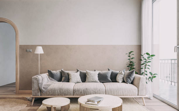 istock Empty nostalgic retro living room with beige sofa, colored cushions, marble coffee tables, and decoration in front of a beige and white colored wall 1438399731