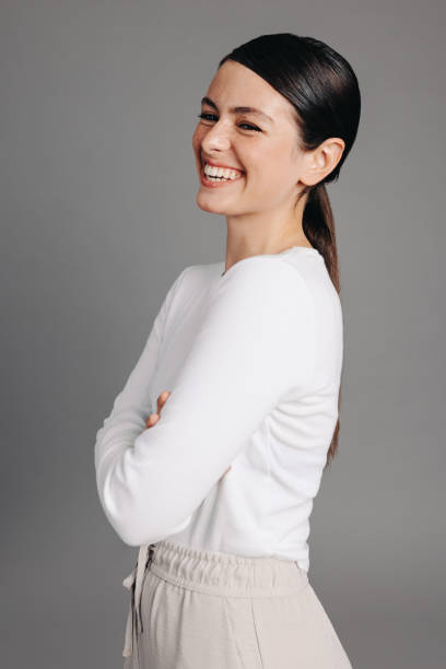 istock Happy young woman laughing while standing against a grey background 1438401022