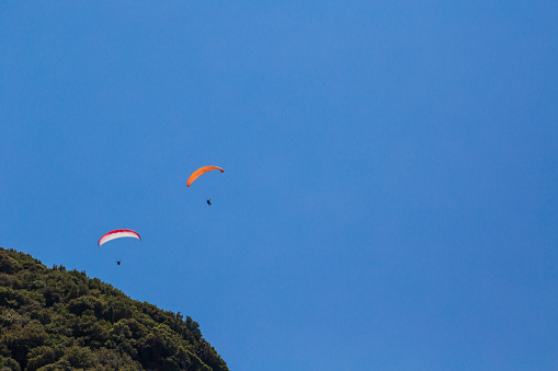 Tandem paragliding against a blue sky, sunny day. Two paragliders in sky.