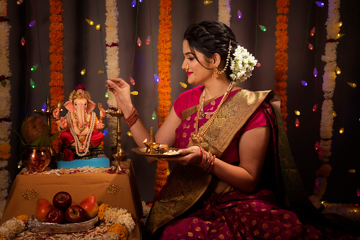 Young Indian woman performing rituals of Ganesh pooja during Ganesh Festival