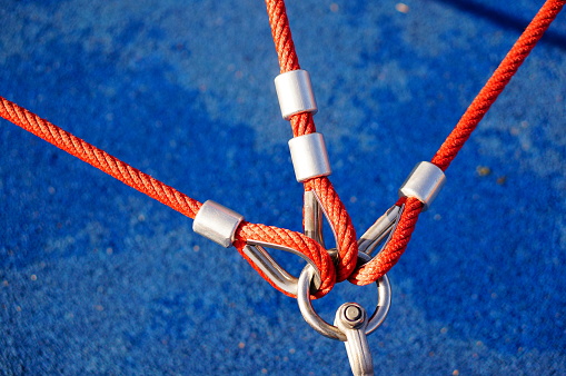 A high angle closeup shot of three red ropes attached to a metal holder with a blue background
