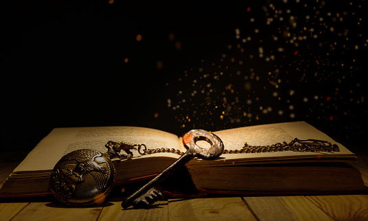 Knowledge is power theme with old key and antique book with magic lights coming down