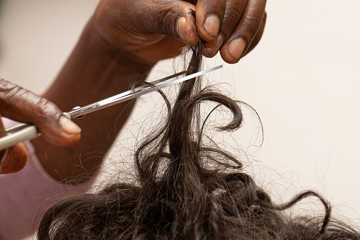 Afro-american hairdresser hands cut with scissors curly hair woman