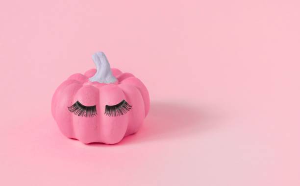 istock Halloween pink pumpkin with makeup, false eyelashes on the pink background, close-up 1438413207