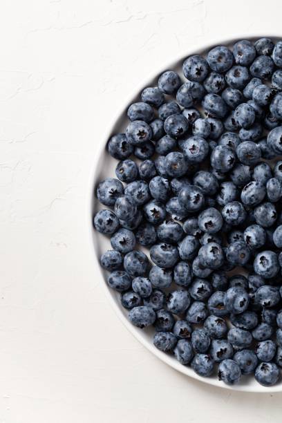 istock Partial view of a white plate filled with blueberries  with white background 1438413996