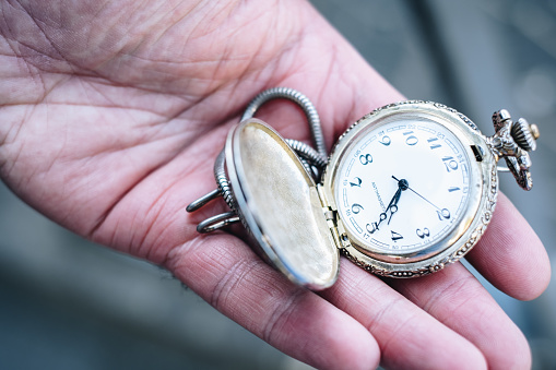 Old metal pocket watch isolated on a white background. Manufactured at the beginning of the 20th century.