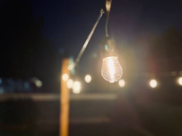 istock Closeup view of a lit light bulb hanging from a cord with selective focus and bokeh 1438414286
