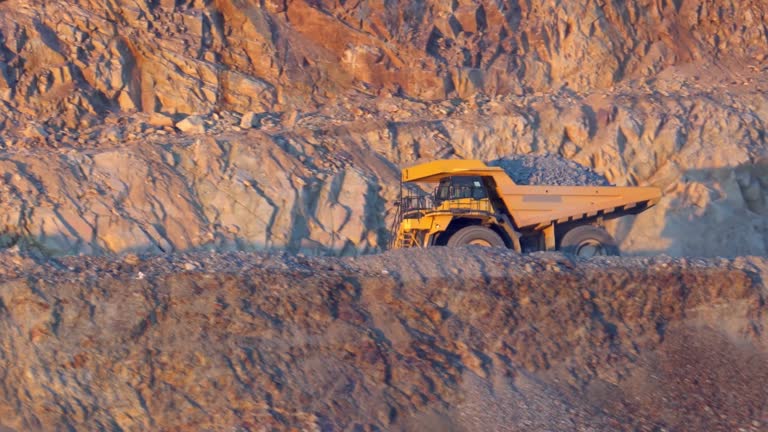 Heavy mining dump trucks driving along the opencast open mine pit, slow motion