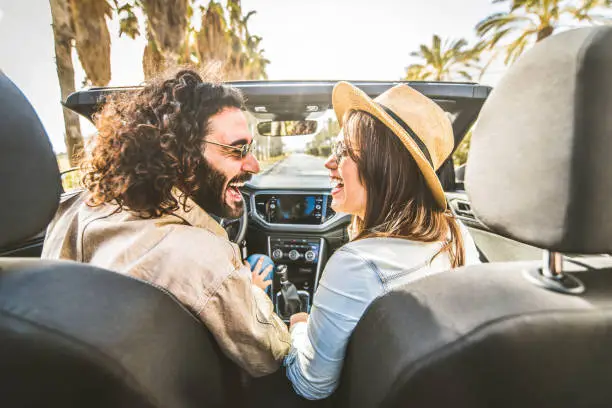 Happy couple driving convertible car enjoying summer vacation - Friends rent cabrio auto on holiday - Roadtrip, freedom, travel and transport rental service concept