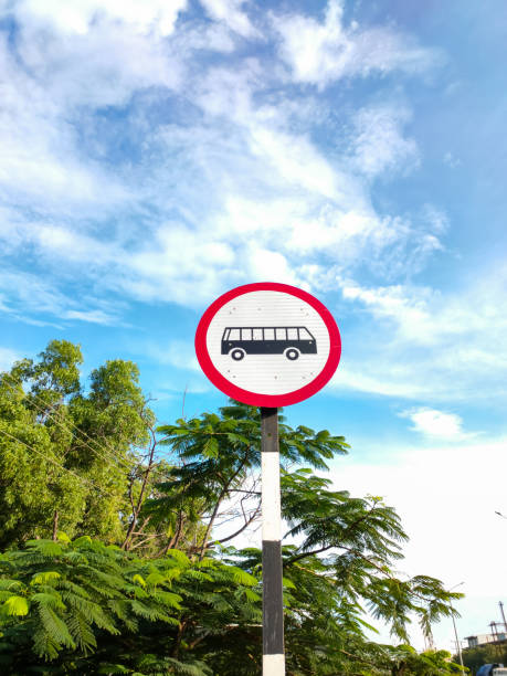 Bus stop sign against white and blue sky