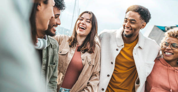 Multiracial friends smiling and having fun hanging outside - University students socializing together in college campus - Friendship concept with guys and girls walking on city street