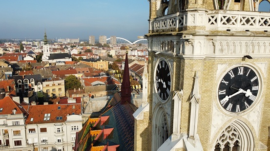 An aerial view of an old architectural building with a clock on a tower in a city in daylight