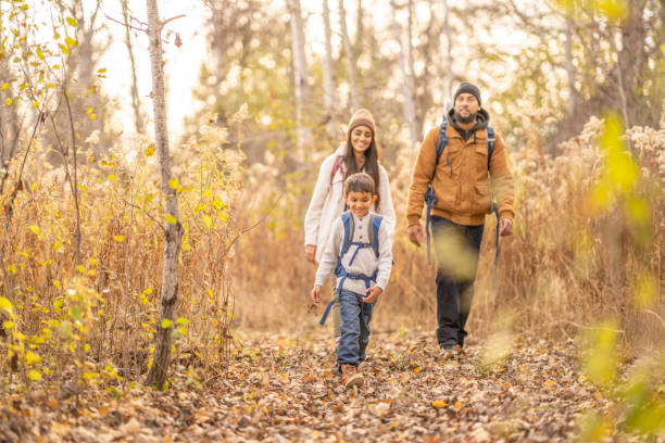 Family Forest Adventures A Mother, Father and two children set out on a hike through the bare woods on a cool fall day.  The Father is carrying the baby in a backpack and the little boy has on a small backpack of supplies for their adventure. 
 They are each dressed warmly in layers as they crunch on the dry leaves underfoot. 6 9 months stock pictures, royalty-free photos & images