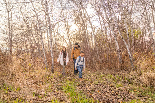 Family Forest Adventures A Mother, Father and two children set out on a hike through the bare woods on a cool fall day.  The Father is carrying the baby in a backpack and the little boy has on a small backpack of supplies for their adventure. 
 They are each dressed warmly in layers as they crunch on the dry leaves underfoot. 6 9 months stock pictures, royalty-free photos & images