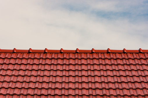 New roof tiles against a cloudy sky. Roofing concept or rooftop repair