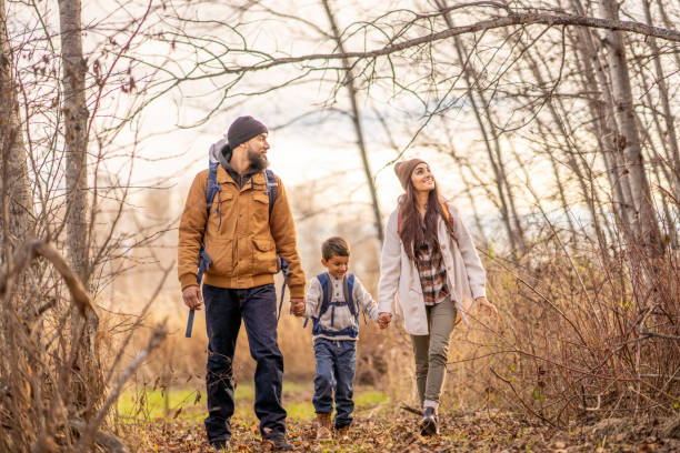 Family Fall Hike A small family of four, consisting of a Mother, Father and two children, hike together in the woods on a cool fall day.  They are each dressed warmly in layers as they spend time together in the fresh air.  The Father is carrying the baby in a backpack and the little boy is carrying a small backpack of supplies for their adventure, as the family walks hand-in-hand. 6 9 months stock pictures, royalty-free photos & images