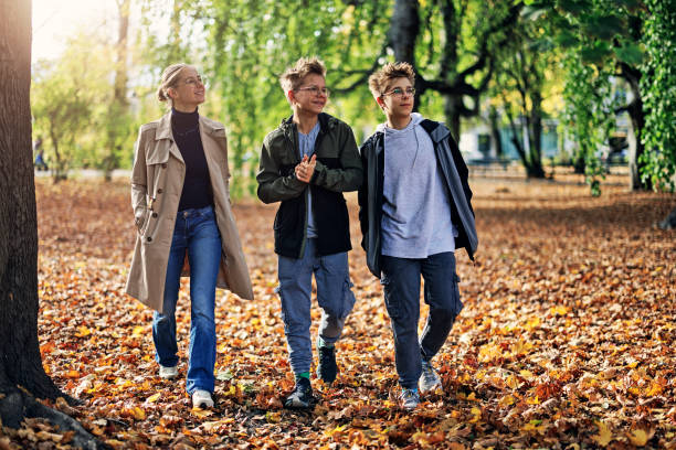 Three teenagers walking in public park on a sunny autumn day. stock photo