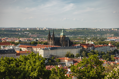 Panoramic Day View of Prague Castle and Saint Vitus Cathedral with green trees in the surroundings and some clouds in the sky