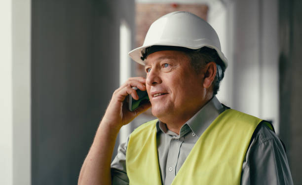 istock Communication, construction worker and project management with businessman and phone call for engineering, designer and architecture. Contact, building and planning with employee and 5g mobile 1438431499