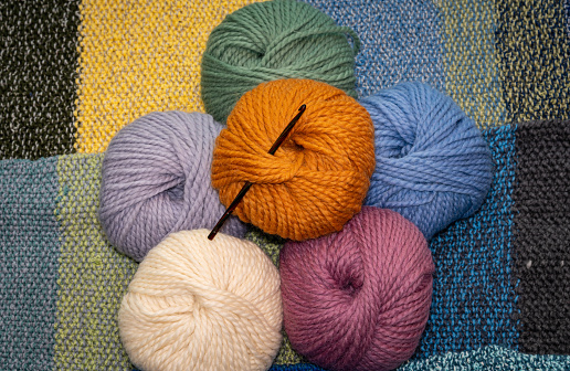 Colorful balls of wool on knitted background, concept of knitting of crocheting as a hobby