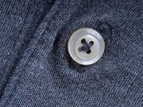 Abstract of black cotton knit shirt with button as center of interest. Abstract macro background with textured cotton material with room for copy.