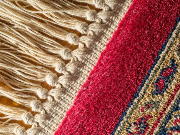 istock Red pattered oriental rug with cream colored fringe as macro background 1438432219