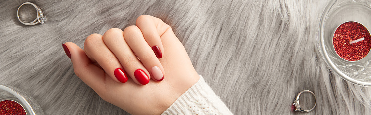 Female hand with nail design Christmas valentines day on gray background. Manicure, pedicure beauty salon concept. Empty space for text