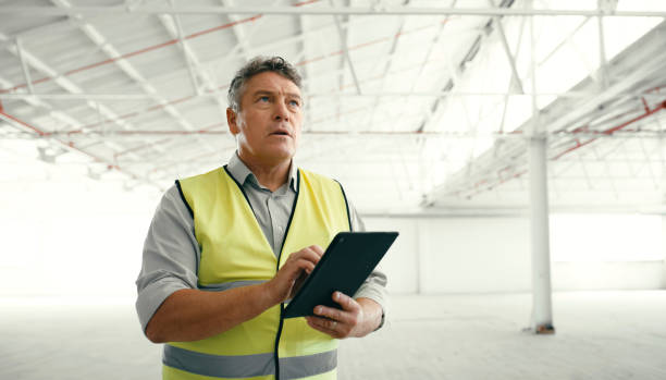 istock Construction worker, building maintenance tablet and contractor check of a man with company data. Digital tech and internet information checking of a warehouse or architecture worker on a job 1438434046
