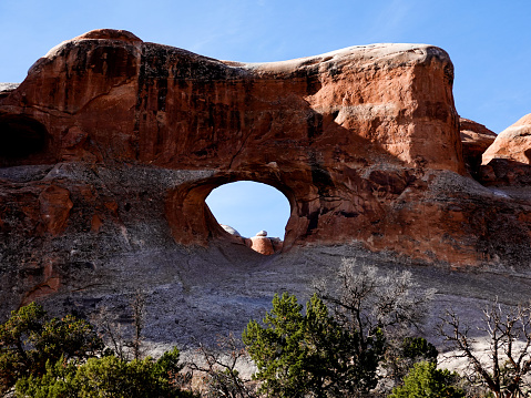 A fit woman hiking in the Cederberg Mountains near Cape Town. Woman stands below the Wolfberg Arch and admires the view over the extreme terrain. Iconic mountain range in South Africa