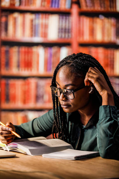 istock Smiling young woman studying for a test in a library 1438437388