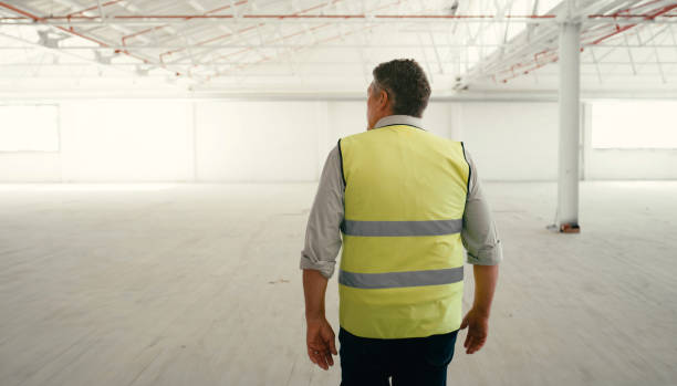 istock Construction worker, building manager or builder man employee looking at empty job site. Back view of construction, buildings and engineer worker boss on a architecture project for engineering 1438437625