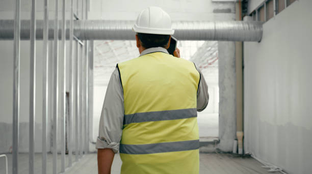 istock Construction site, contractor and man project management on phone call planning, consulting and logistics, industrial engineering or building industry. Back of architect manager talking on smartphone 1438437628