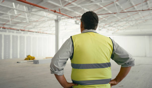 istock Construction worker, building maintenance and architect planning worker checking a job site.  Back view of industrial engineer, architecture and buildings analyst man employee in a empty warehouse 1438438685