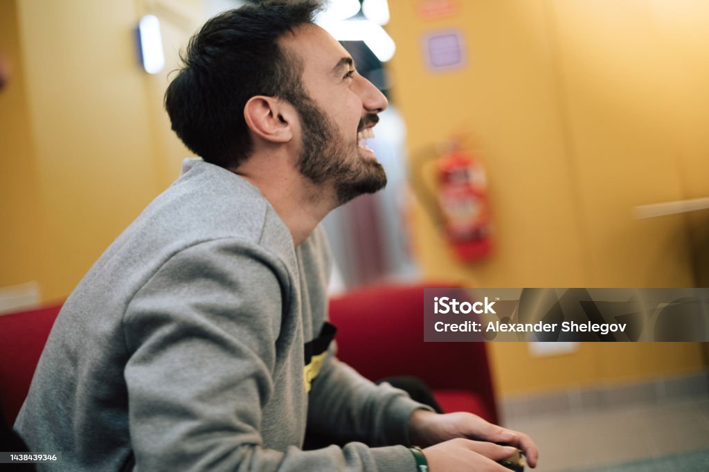 Male portrait of beard man who playing video game on digital console indoors. People holding gamepad in the hands. Xbox and Playstation concept photography. 20-24 Years Stock Photo