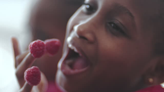 Twin girls playing with raspberries